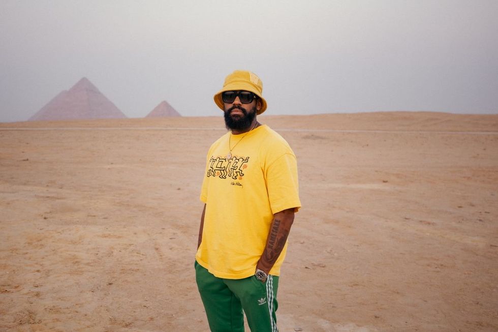 PJ Morton stands in the Sahara Desert, with the pyramids of Egypt behind him.