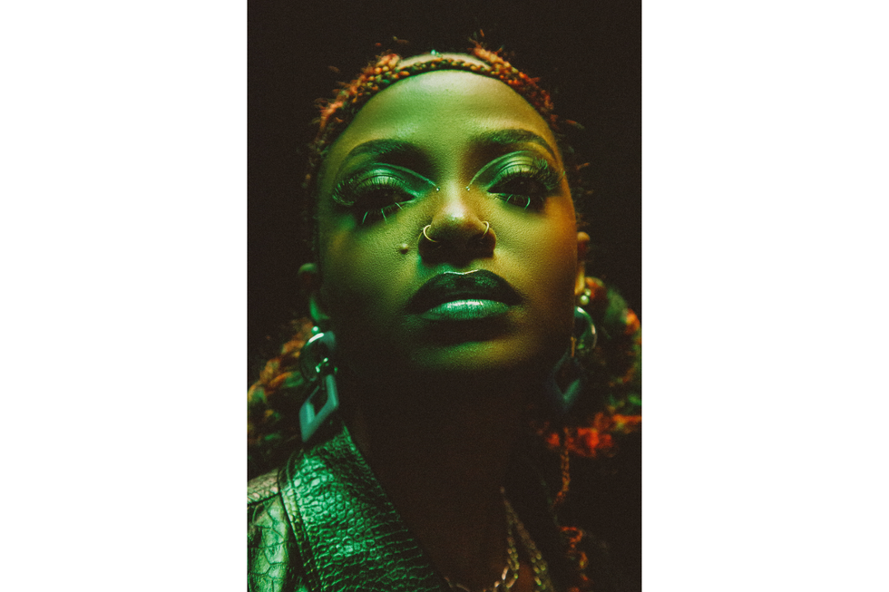 Kenyan artist Xenia Manasseh illuminated in green while wearing a leather jacket